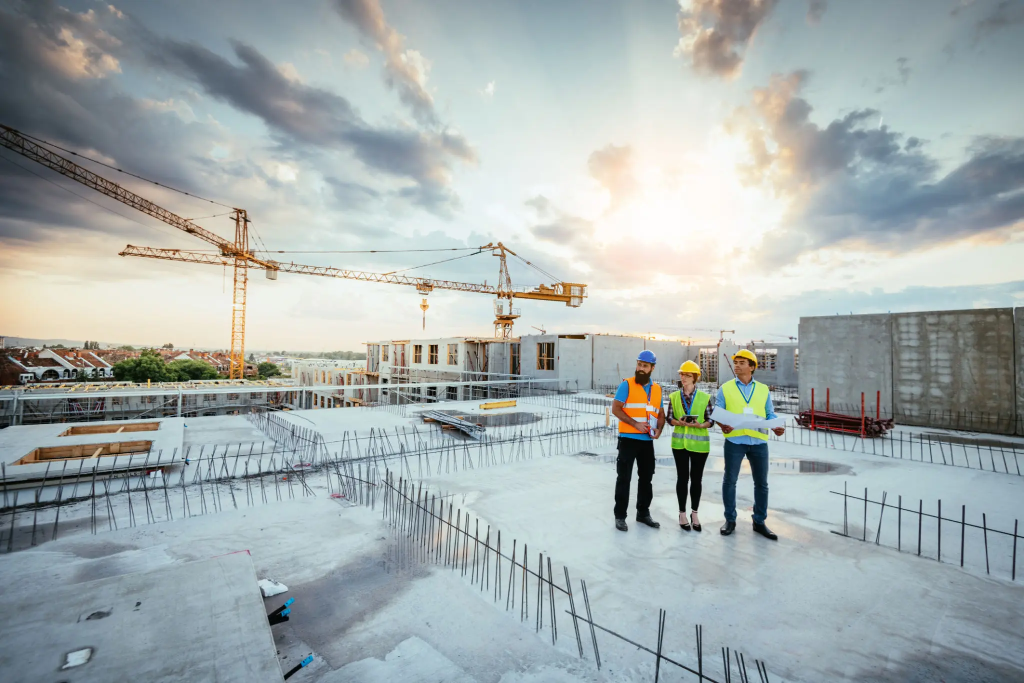 Construction workers on building site at sunset.